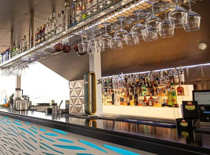 Backlit bar counter with hanging glasses and spirits at Sky Bar Veramar, Fuengirola