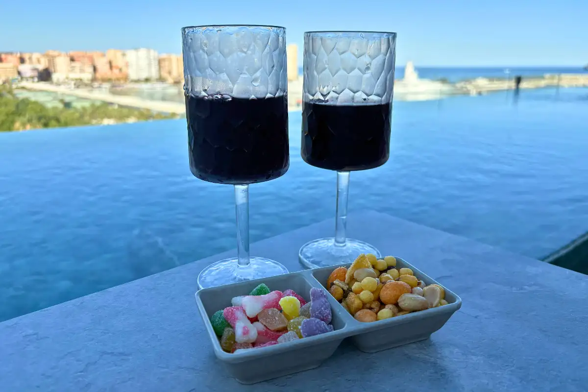 Two glasses of red wine and snacks by the infinity pool at Lolita Skyview, Malaga