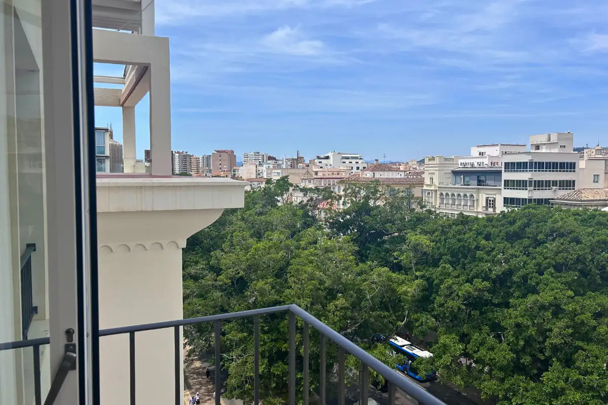 Balcony view over leafy park gardens and the city at Petit Palace La Equitativa, Malaga