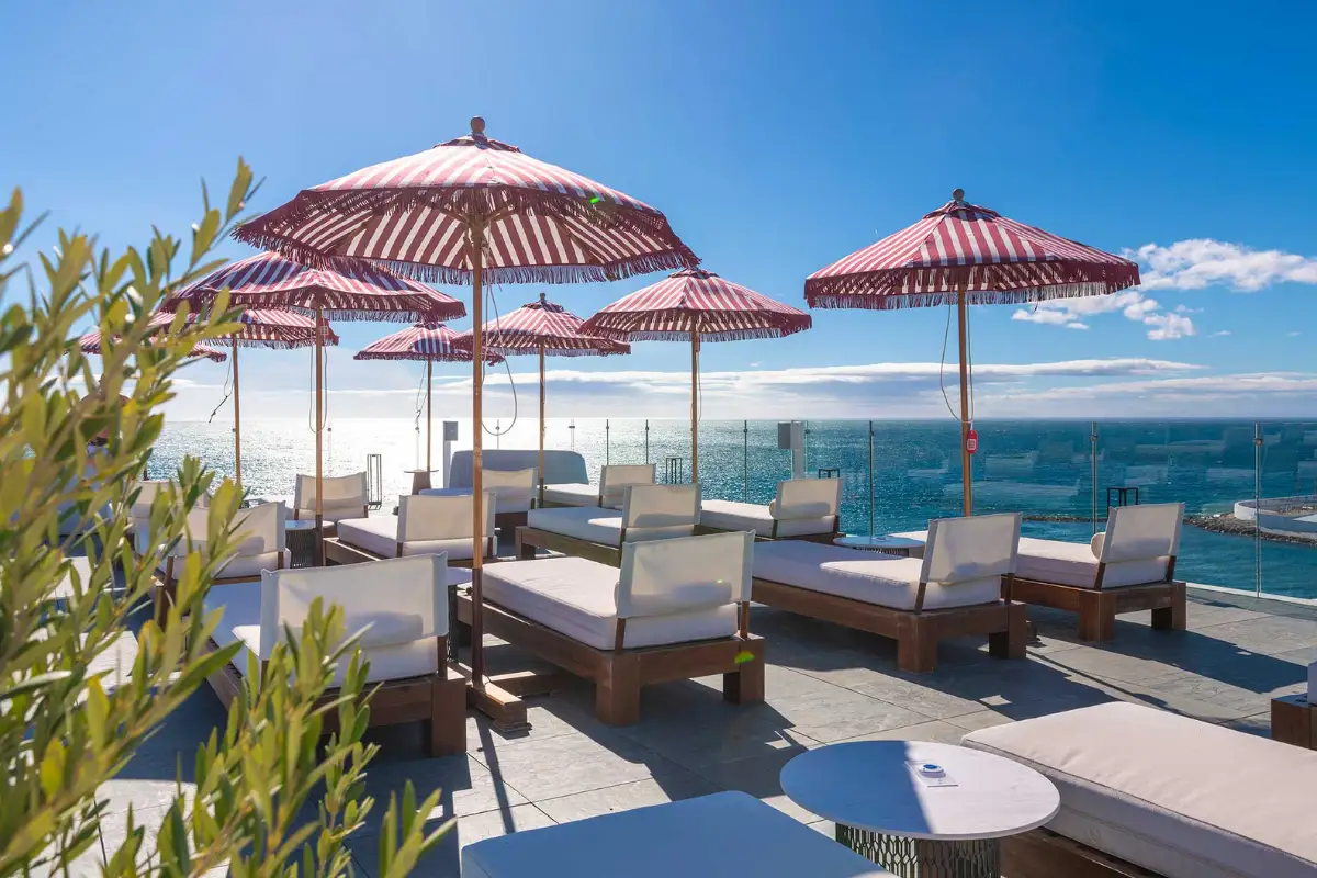 Sun loungers and red parasols facing the sea at Edge at El Fuerte, Marbella