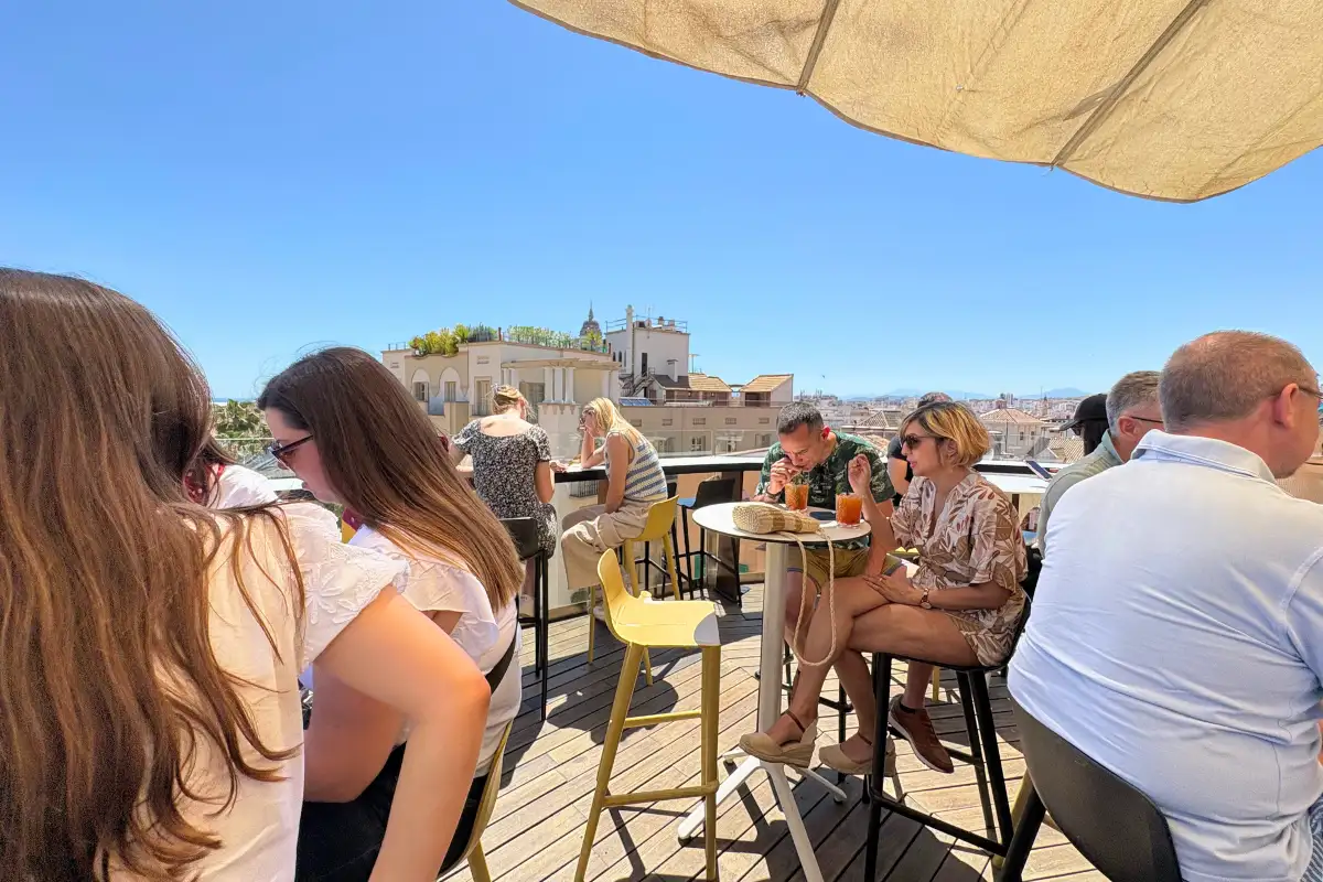 Guests at high tables under an umbrella with city views at La Terraza de Alcazaba in Malaga
