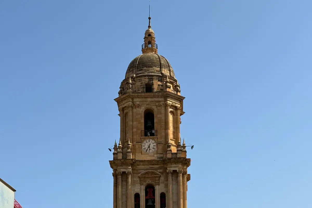 Malaga Cathedral clock tower against blue sky seen from Terraza Catedral rooftop bar